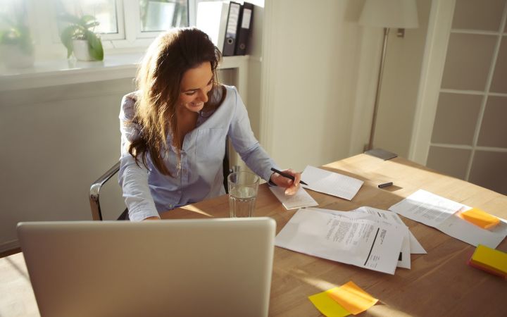 Pretty young female writing notes smiling beautiful caucasian female with laptop computer working from home office H Tg1k GI4 Kl